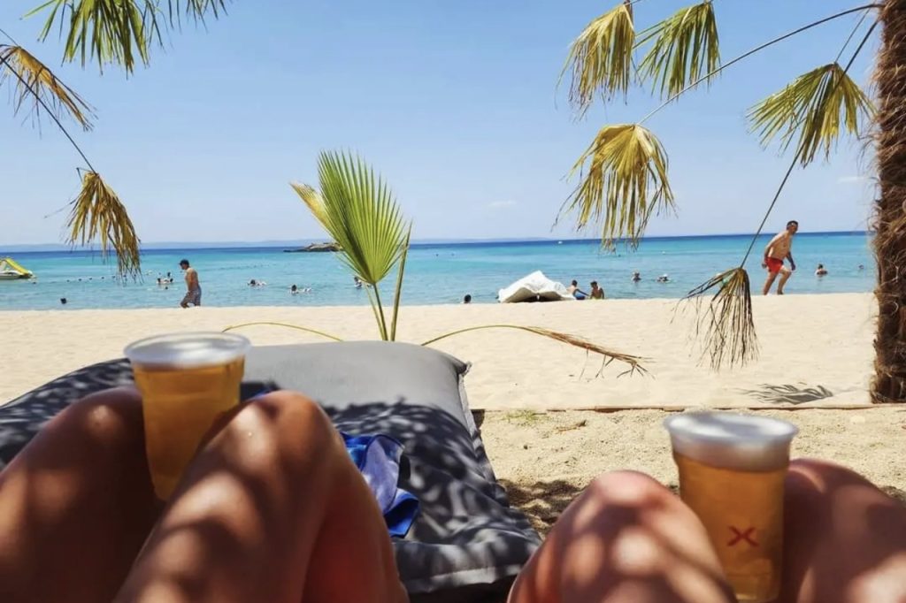 Kalogria Beach Sitonija Halkidiki, peščana plaža sa tirkiznim morem i ležaljkama u hladu palmi