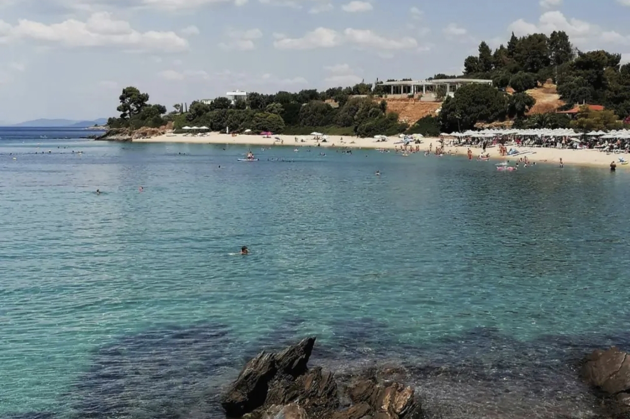 Uređena plaža u Grčkoj sa čistom vodom i turistima tokom letnje sezone