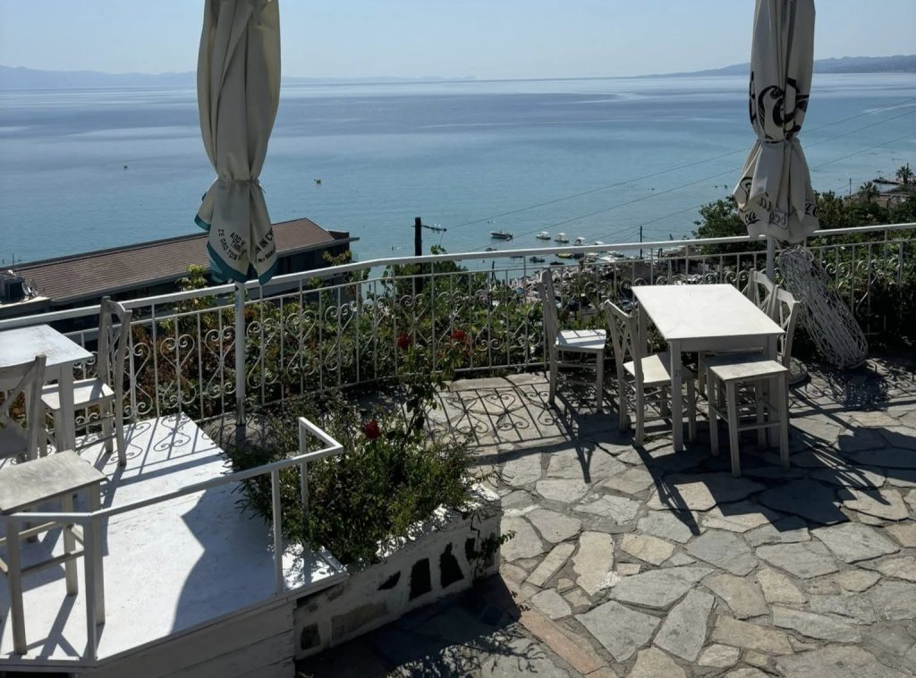 Pogled sa terase u Kalitei na more i obalu u Grčkoj sa stolovima i belim nameštajem