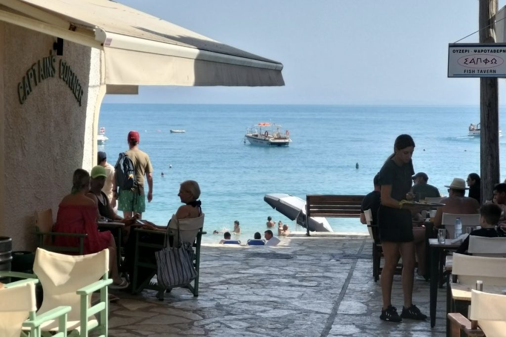 Taverna u Lefkadi uz samu plažu sa pogledom na more i gostima koji uživaju u ručku