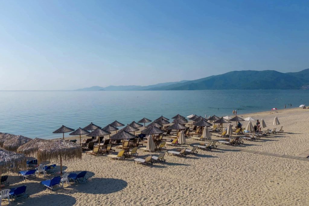 Peščana plaža u Nea Vrasni sa ležaljkama i mirnim morem